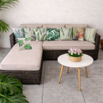 Funda de cojín hojas tropicales en sofá de terraza con mesa blanca y decoración natural