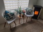 Funda de cojín hojas tropicales en sillas decorativas junto a mesa auxiliar de madera